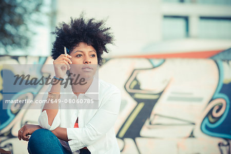 Young woman smoking cigarette in front of graffiti wall Young woman smoking cigarette in front of graffiti wall