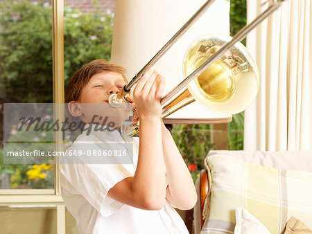 Boy practicing trombone in sitting room