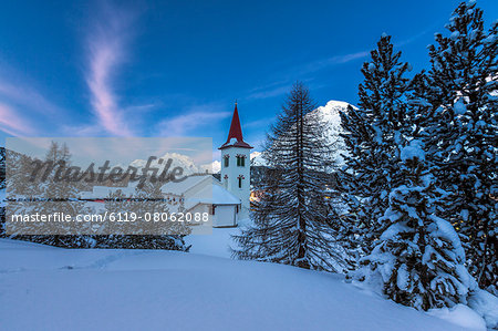 The white church of Maloja Pass in the winter fairy-tale landscape of the Engadine Valley at the blue hour, Graubunden, Switzerland, Europe