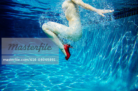 Mature woman, nude, wearing only red high heels, underwater view, low section