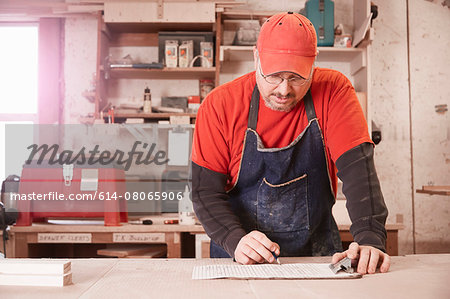 Cabinet maker checking blueprint at workshop bench