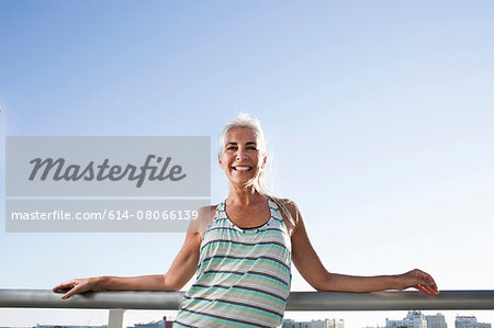 Portrait of mature woman in sports clothing leaning against city balcony Portrait of mature woman in sports clothing leaning against city balcony