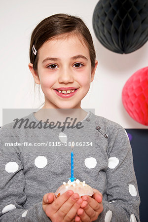 Girl on birthday party holding cupcake with burning candle, Munich, Bavaria, Germany