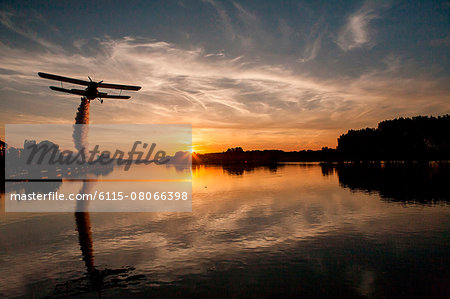 Biplane flying over Drava river at sunset, Osijek, Croatia