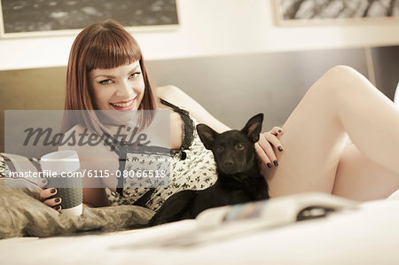 Young woman with pet dog relaxing in bed