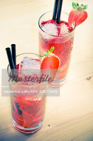 glasses of strawberry cocktail with ice on old wood table, old style atmosphere