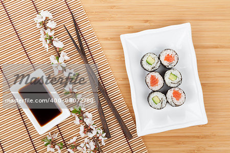 Sushi maki set and sakura branch on bamboo table