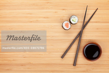 Maki sushi, chopsticks and soy sauce on bamboo wooden table background with copy space