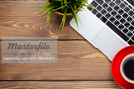 Office desk table with laptop computer, coffee cup and flower. Top view with copy space