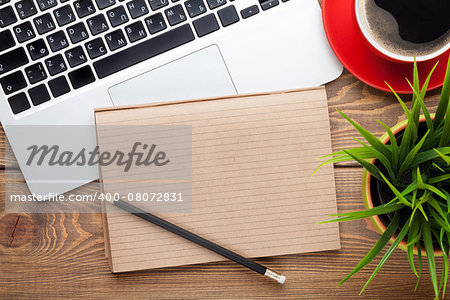 Office desk table with computer, supplies, coffee cup and flower. Top view with copy space