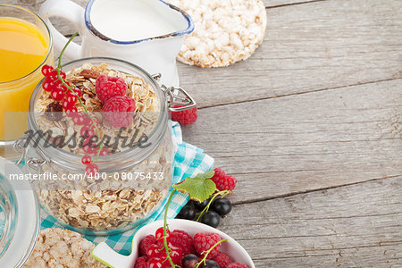 Healthy breakfast with muesli, berries, orange juice and milk. On wooden table