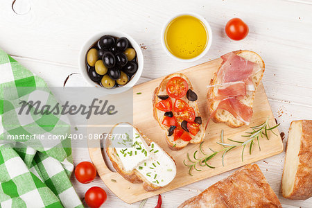 Bruschetta with cheese, tomatoes and prosciutto on cutting board