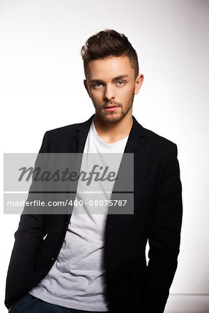 young handsome man , in black jacket , informal pose . he is looking at the camera