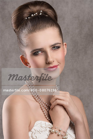 close-up portrait of fine brunette lady with elegant hair-style, stylish make-up and precious pearl necklace. Looking in camera with lovely expression