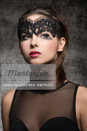 Pretty, elegant, stunning brunette woman with nice hairstyle covered her neck and mask on the face. she has hot nice nark makeup. She is wearing half transparent top.