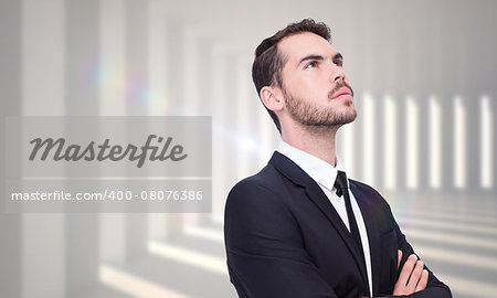 Thinking businessman with his arms crossed against curved white room