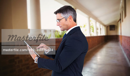 Mid section of a businessman touching tablet against hallway