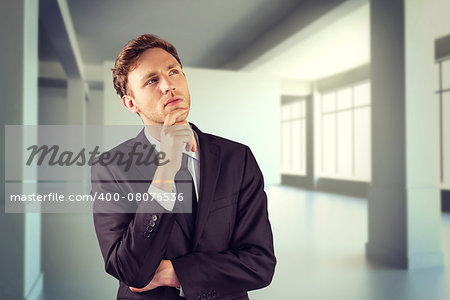 Young businessman thinking with hand on chin against white room with screen