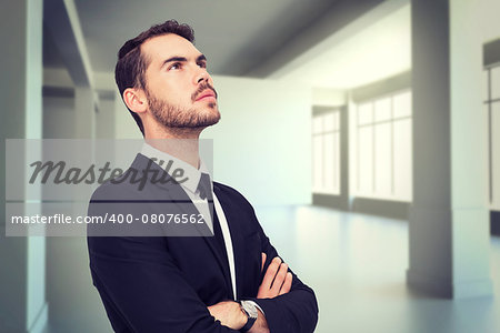 Thinking businessman with his arms crossed against white room with screen