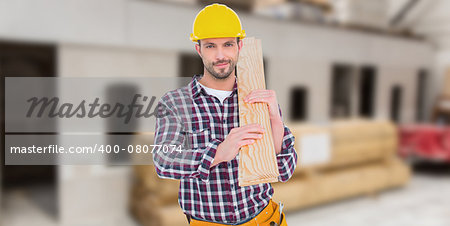 Handyman holding wood planks against workshop