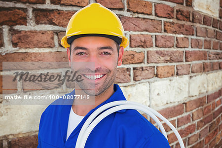 Electrician carrying wires over white background against red brick wall