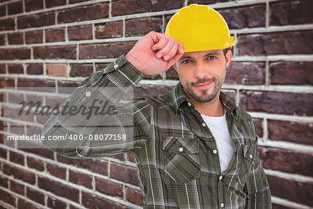 Smiling Handyman holding helmet  against red brick wall