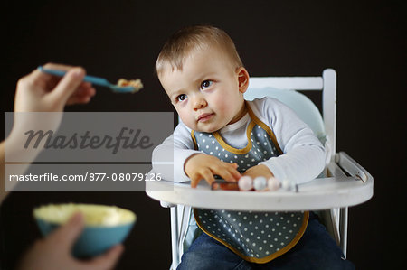 A 15 months baby boy eating on his high chair
