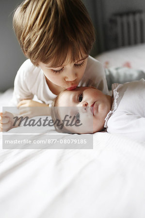 A 5 years old boy kissing his 4 month baby sister