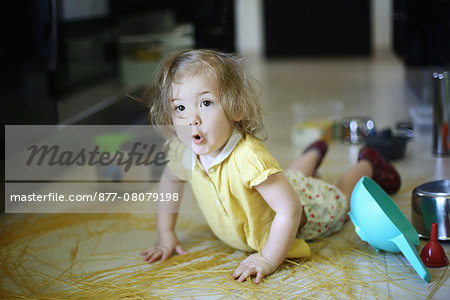 A 2 years old little girl posing in a kitchen in which she made the mess