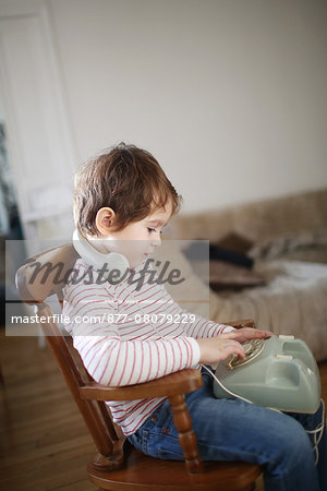 Little boy making a phone call with an old phone