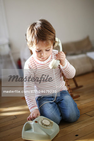 Little boy making a phone call with an old phone