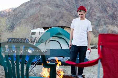 Young woman looking down at campfire, Anza-Borrego Desert State Park, California, USA