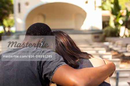 Young couple sitting together, embracing, rear view