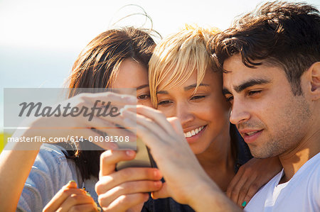 Three friends looking at smartphone, outdoors