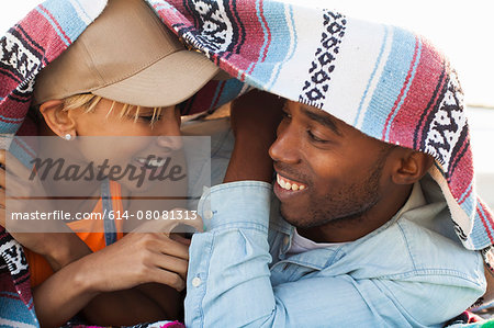 Young couple laughing together under picnic blanket