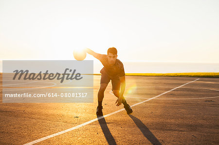Young man, dribbling basketball on court, outdoors