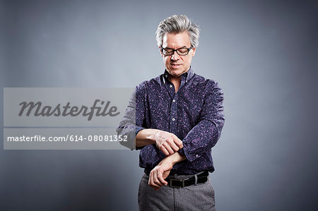 Studio portrait of mature businessman rolling up his sleeves