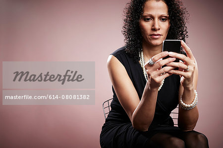 Studio portrait of mature businesswoman reading smartphone messages