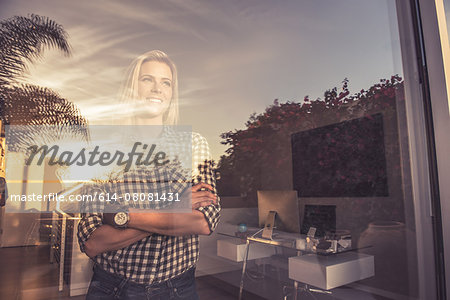 Portrait of young woman watching sunset from suburban window