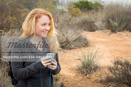 Young female hiker choosing music on smartphone