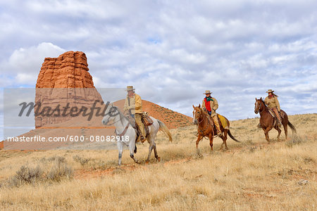 Cowboy and Cowgirls Riding Horses with Castel Rock in the background, Shell, Wyoming, USA