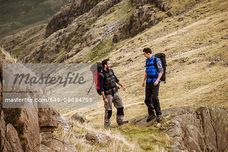 Two young male hiking friends laughing and chatting, The Lake District, Cumbria, UK