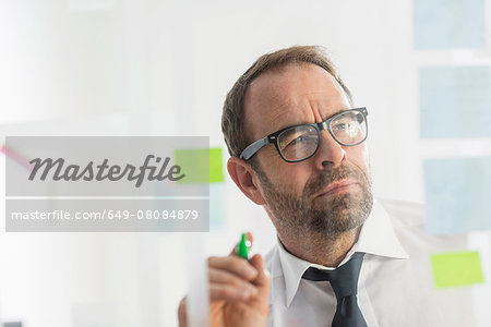 Businessman writing ideas on adhesive notes for glass wall