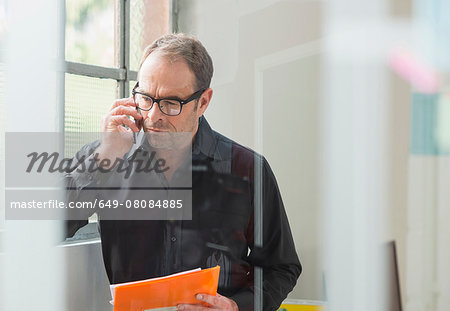 Businessman reading paperwork and chatting on smartphone