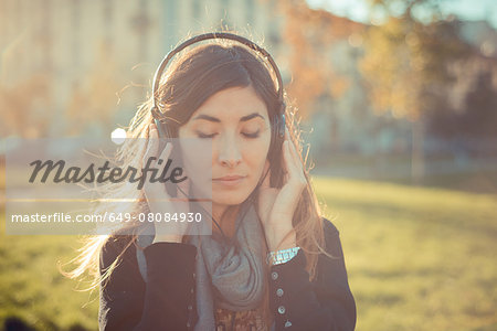 Mid adult woman with eyes closed listening to headphones in park