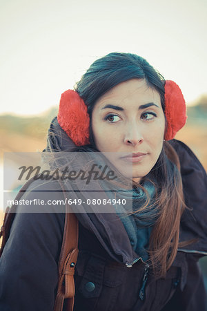 Mid adult woman wearing red ear muffs in park