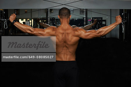 Mid adult man, lifting weights, rear view