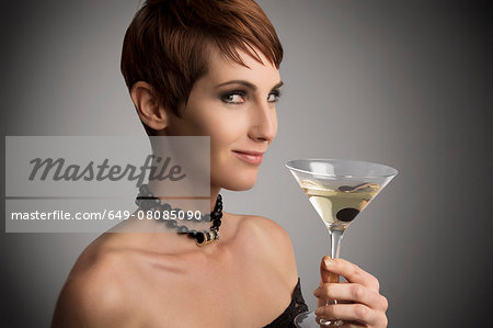 Studio portrait of woman looking sideways holding cocktail