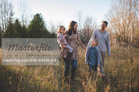 Young couple with son and daughter strolling in field