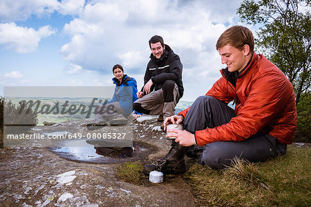 Male and female hikers preparing camping stove on Guise Cliff, Pateley Bridge, Nidderdale, Yorkshire Dales